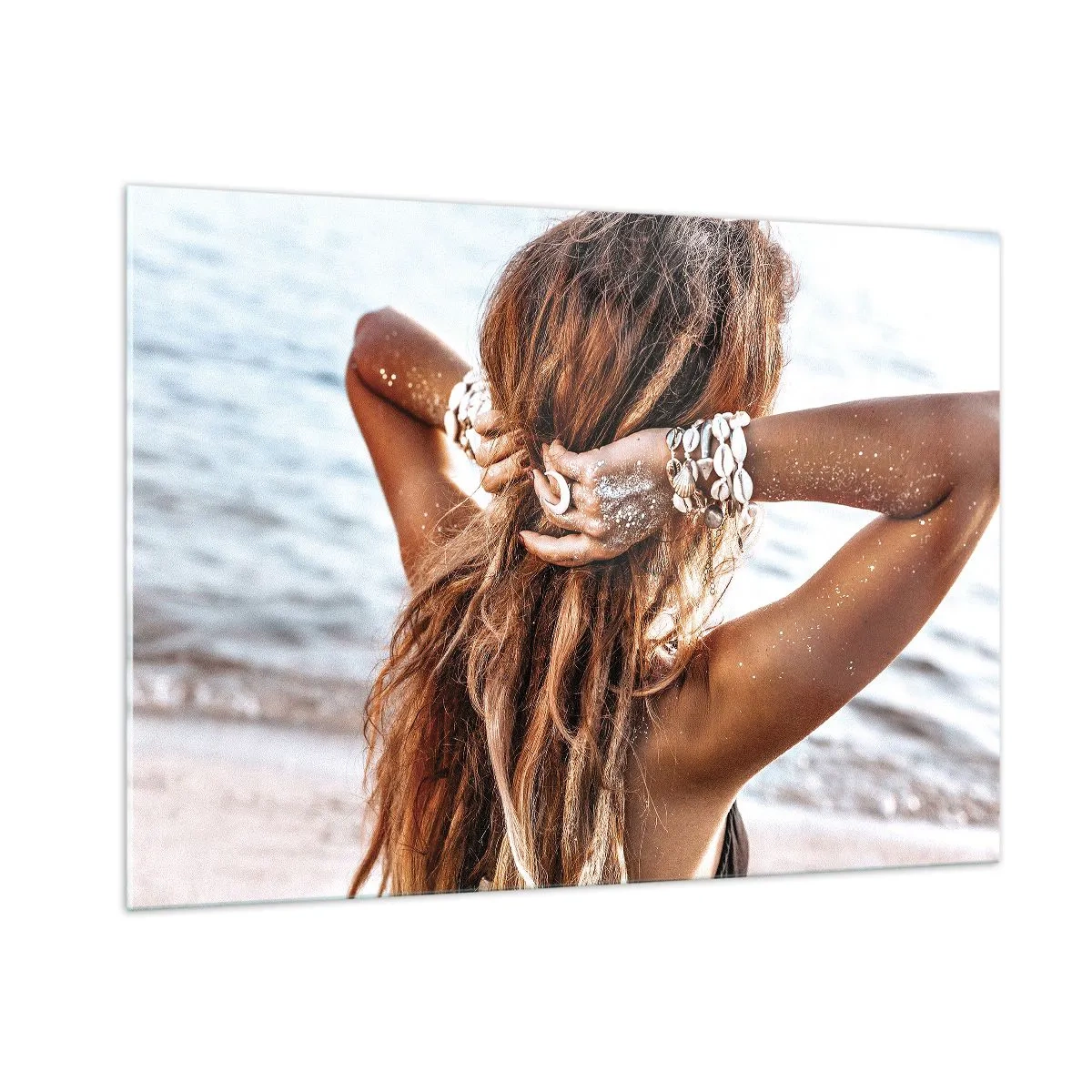 Quadro su vetro - Una donna con i capelli lunghi sulla spiaggia, circondata da conchiglie e sabbia. - 100x70cm - Sorella dell'acqua e del sole - Decorazione murale moderna per soggiorno e camera da letto ARTTOR
