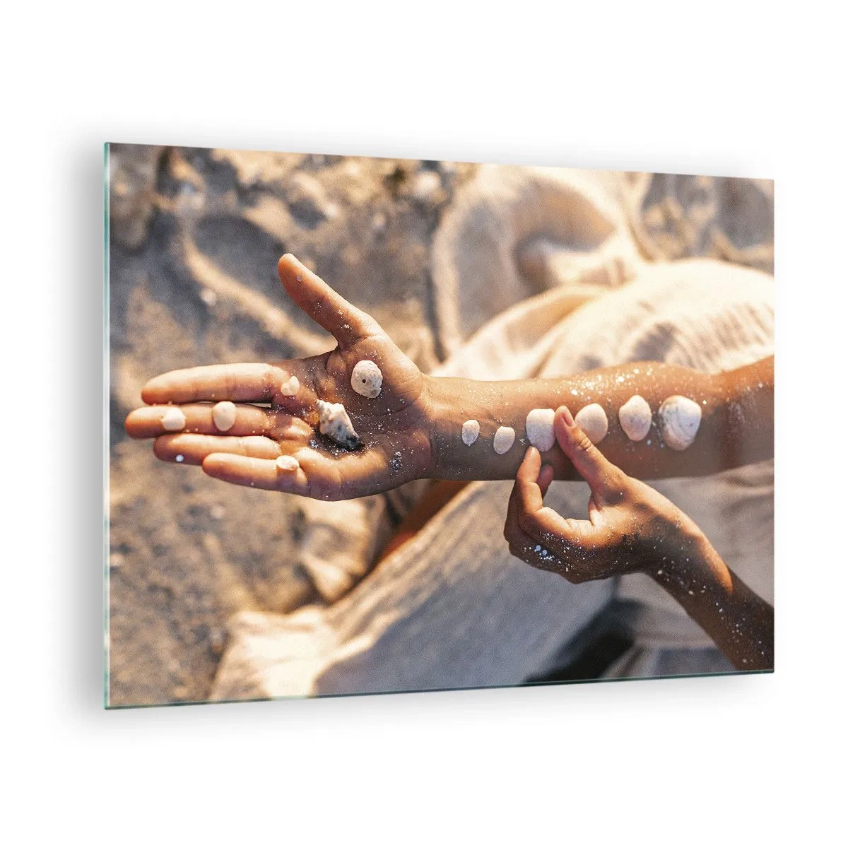 Quadro su vetro - Mani di bambino con conchiglie su uno sfondo di sabbia e tessuto - 70x50cm - La bellezza a portata di mano - Decorazione murale moderna per soggiorno e camera da letto ARTTOR