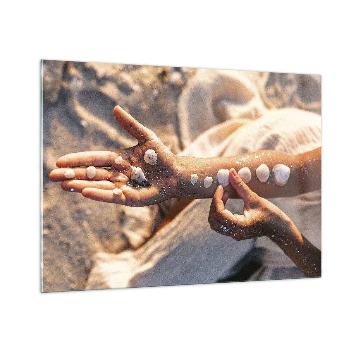 Quadro su vetro - Mani di bambino con conchiglie su uno sfondo di sabbia e tessuto - 100x70cm - La bellezza a portata di mano - Decorazione murale moderna per soggiorno e camera da letto ARTTOR
