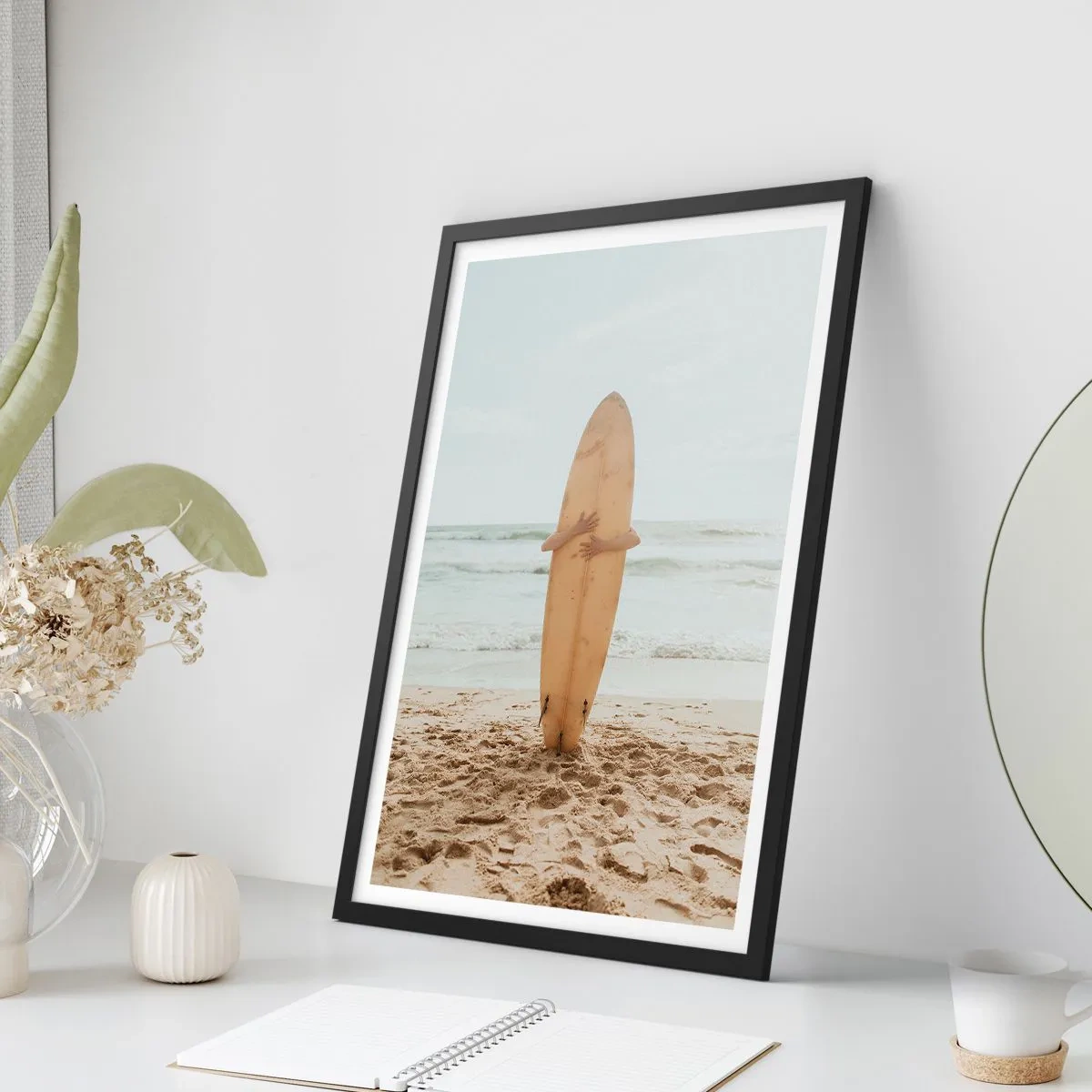 Poster in cornice nera - Una persona che tiene in mano una tavola da surf su una spiaggia, con vista sul mare. - 50x70cm - Amore per le onde - Decorazione murale moderna per soggiorno e camera da letto ARTTOR