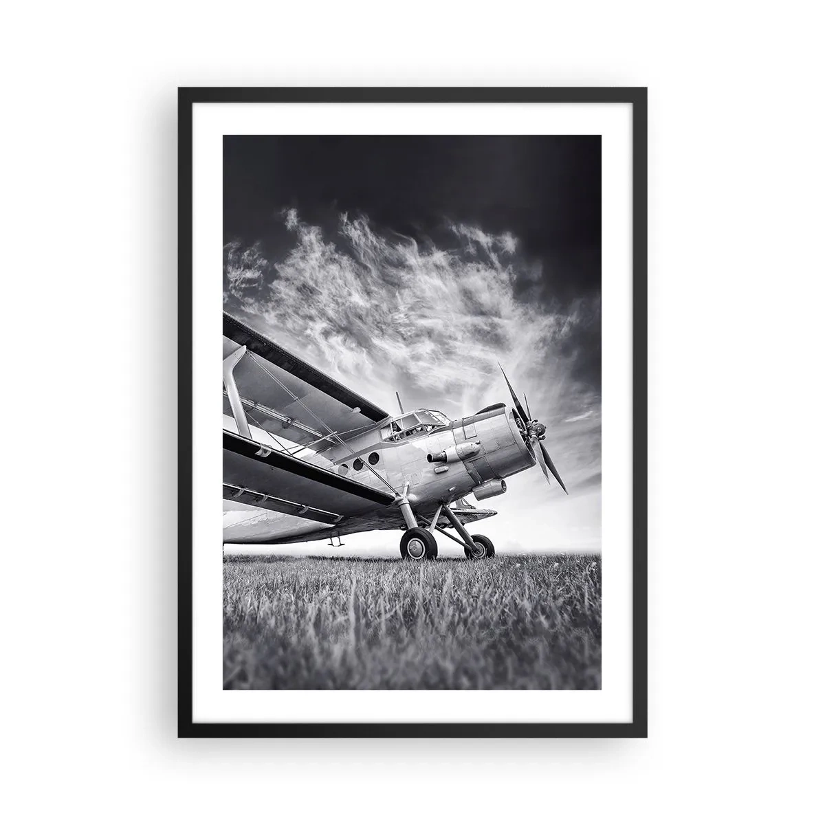 Poster in cornice nera - Un'immagine in bianco e nero di un aereo contro un cielo dinamico. - 50x70cm - Giramondo alato  - Decorazione murale moderna per soggiorno e camera da letto ARTTOR