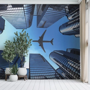 Fotomurali Premium Sand - Grattacieli moderni e un aereo che vola nel cielo - 100x70cm - Panorama dal canyon di vetro - Decorazione murale moderna per soggiorno e camera da letto ARTTOR