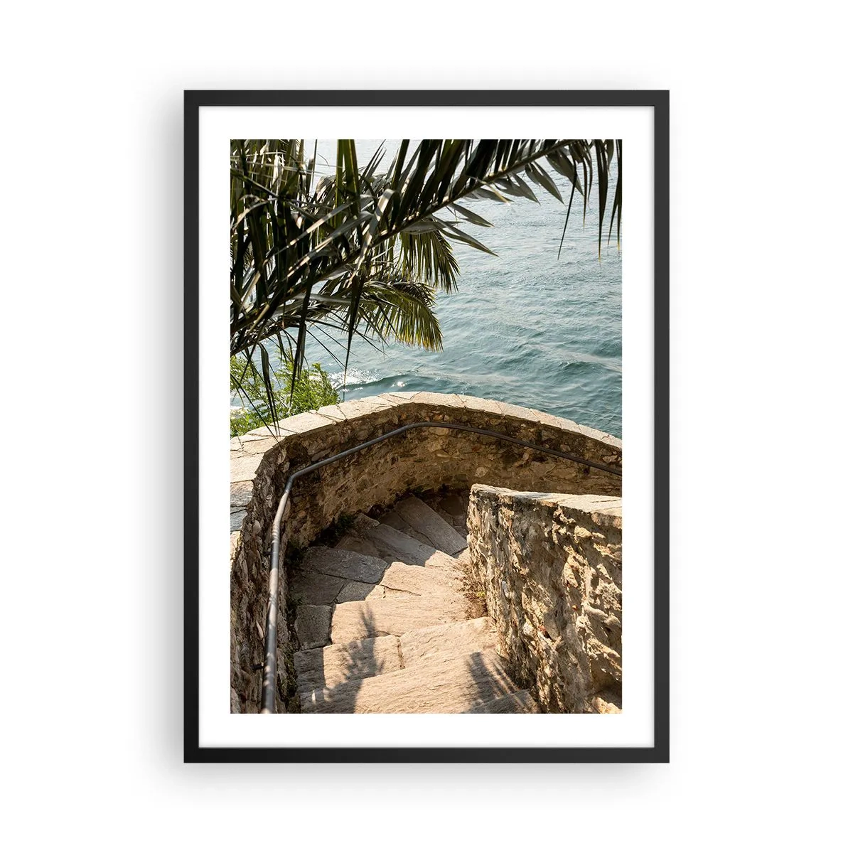 Poster in cornice nera - Una scala a chiocciola in pietra che conduce verso il mare, fiancheggiata da palme - 50x70cm - Sotto il sole d'Italia - Decorazione murale moderna per soggiorno e camera da letto ARTTOR