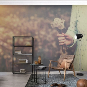 Fotomurali Premium Sand - Una mano che tiene i denti di leone in un campo sfocato - 100x70cm - Fermali per favore - Decorazione murale moderna per soggiorno e camera da letto ARTTOR